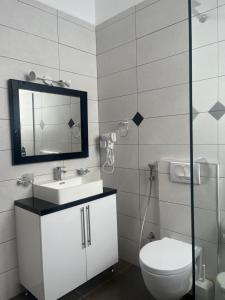 y baño con aseo, lavabo y espejo. en Saranda Hotel, en Sarandë
