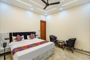 a bedroom with a bed with chairs and a ceiling fan at The Grand Mansion Hotel in Greater Noida