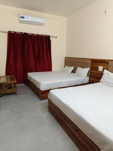 a bedroom with two beds and a red curtain at Hotel Shiv Ganga in Rishīkesh