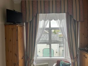 a window with curtains and a television in a room at Ashmore House in Cashel