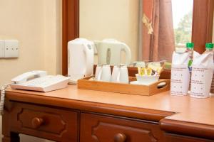 a wooden dresser with a counter top with a telephone and cups at Hotel Lakefield in Kandy