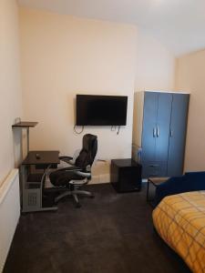 a bedroom with a desk and a chair and a television at Lovely Bedroom with Free parking in Walsall
