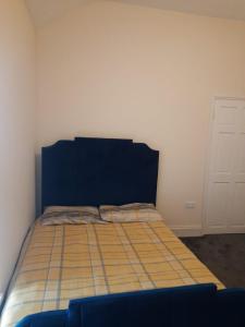 a bedroom with a bed with a blue headboard at Lovely Bedroom with Free parking in Walsall