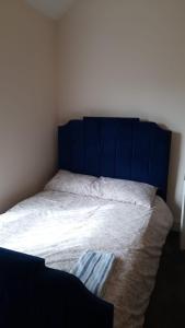 a bed with a blue headboard in a bedroom at Lovely Bedroom with Free parking in Walsall