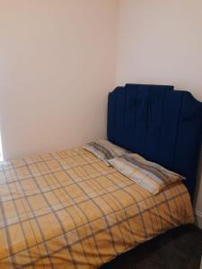 Bett mit blauem Kopfteil in einem Zimmer in der Unterkunft Lovely Bedroom with Free parking in Walsall