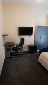 Zimmer mit einem Stuhl, einem Schreibtisch und einem TV in der Unterkunft Lovely Bedroom with Free parking in Walsall