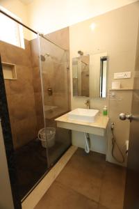 ein Bad mit einem Waschbecken und einer Dusche in der Unterkunft Queens Hotel -Yellow Lake Resorts &Spa -Yercaud in Yercaud