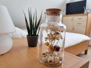 a glass bottle with flowers and rocks on a table at Apartmaji pri Ticelnu in Bovec