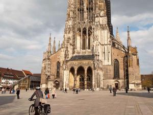 Eine Frau, die vor einer Kathedrale Fahrrad fährt in der Unterkunft ibis Ulm City in Ulm