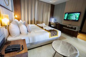 una camera d'albergo con un grande letto e una TV di AJ GRAND ELITE HOTEL a Mangalore
