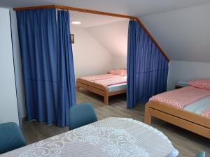 a room with two beds and blue curtains at turistična kmetija pr mark in Trebče