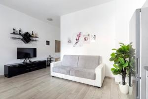 a white living room with a couch and a tv at Luciano Secret Garden Apartment in Rome