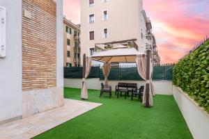 un patio con césped verde, mesa y sillas en Secret Garden Apartment, en Roma