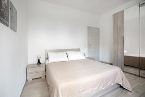 a white bedroom with a large bed and a mirror at Luciano Secret Garden Apartment in Rome