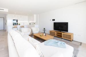 sala de estar blanca con sofá blanco y TV en Luxury House Chaparral Golf E70 by AORA STAY, en La Cala de Mijas