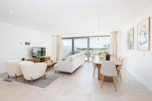 Una sala de estar con muebles blancos y una mesa y sillas. en Luxury House Chaparral Golf E70 by AORA STAY, en La Cala de Mijas
