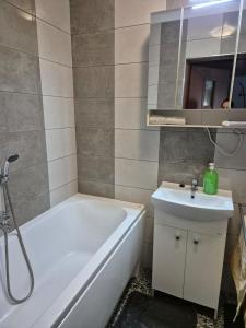 Un baño con bañera blanca y lavabo. en Apartament Bunsha Kraków, en Cracovia