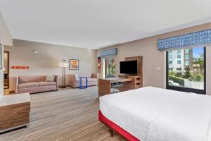 オーランドにあるHampton Inn & Suites Orlando-Apopkaのベッドとリビングルームが備わるホテルルームです。