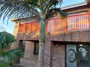 a palm tree in front of a brick building at Erik's Place in Gqeberha