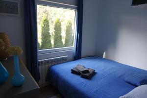 a bedroom with a blue bed and a window at Domek nad Wartą - Park krajobrazowy in Konopnica