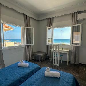 a bedroom with two beds and a desk with a view of the ocean at Alios apartment in Rhodes Town