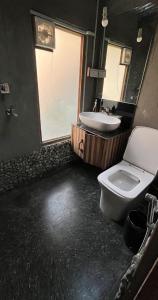W łazience znajduje się umywalka, toaleta i lustro. w obiekcie Aloha Riverside w mieście Kasol