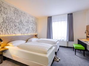 een hotelkamer met drie bedden en een muurschildering bij ibis Styles Halle in Halle an der Saale