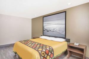 a room with a bed with a large picture on the wall at Super 8 by Wyndham National City Chula Vista in National City