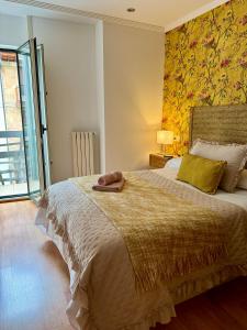 a bedroom with a large bed with a yellow wall at Balcón del Rosal in Oviedo
