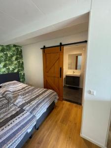 a bedroom with a bed and a bathroom with a sink at Blossom Barn Lodges in Oudewater