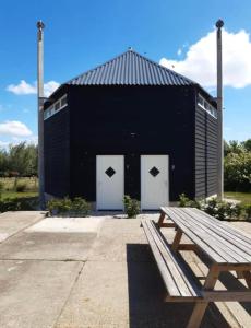 a black building with white doors and a wooden bench at Blossom Barn Lodges in Oudewater
