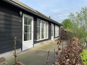 a black house with white doors and windows at Blossom Barn Lodges in Oudewater