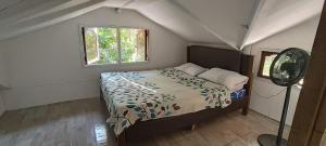 um quarto com uma cama, uma janela e uma ventoinha em Jorge & Pony House 2 em El Nido