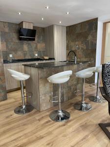 a kitchen with three bar stools in front of a counter at SOLGUEST Apt ESTEPONA CENTRO 1ª LINEA DE PLAYA in Estepona