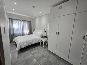 a white bedroom with a bed and a table at No8@Mosselbay - Central Mosselbay 1 Bedroom Apartment in Mossel Bay