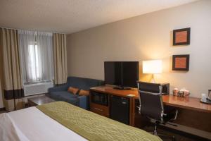 a hotel room with a bed and a desk with a television at Comfort Inn & Suites in Erie