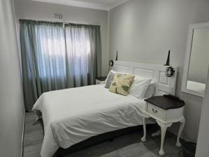 a bedroom with a white bed and a night stand at No8@Mosselbay - Central Mosselbay 1 Bedroom Apartment in Mossel Bay