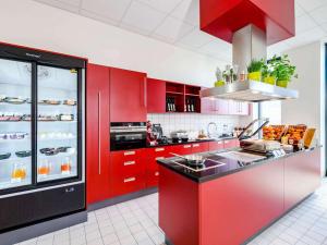 une cuisine avec des placards rouges et un comptoir rouge dans l'établissement Aparthotel Adagio Bremen City, à Brême