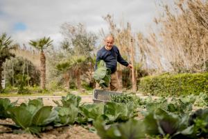 Ein älterer Mann steht in einem Garten mit Pflanzen in der Unterkunft Kempinski Hotel San Lawrenz in San Lawrenz