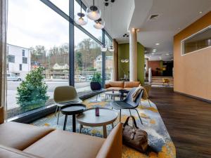 a lobby with couches and chairs and a large window at ibis Styles Coburg in Coburg
