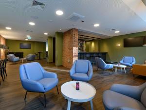 a waiting room with blue chairs and a table at ibis Styles Coburg in Coburg