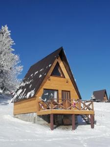 Cabaña de madera con techo negro en la nieve en Koliba Luča Smrčevo Brdo, en Žabljak
