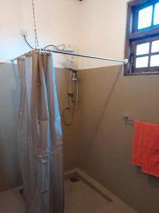 La salle de bains est pourvue d'une douche avec rideau de douche. dans l'établissement Sunnyside Bungalow, à Naula