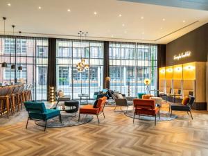 a lobby with chairs and tables and windows at ibis Styles Bielefeld City in Bielefeld