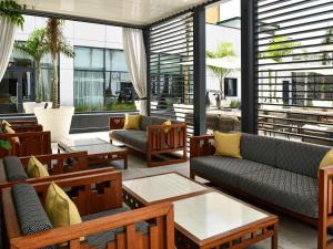 a living room with couches and tables and windows at Mövenpick Hotel Abidjan in Abidjan