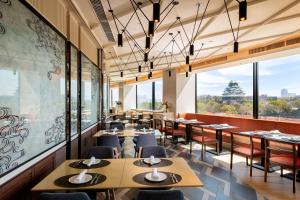 Doubletree By Hilton Osaka Castle في أوساكا: مطعم بطاولات وكراسي ونوافذ كبيرة