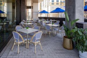 a patio with tables and chairs and blue umbrellas at Tempo By Hilton Nashville Downtown in Nashville