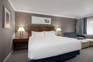 a bedroom with a large white bed and a blue chair at Radisson Hotel Corning in Corning