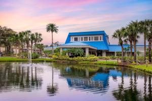 a house with palm trees in front of a lake at Hilton Vacation Club Aqua Sol Orlando West in Orlando