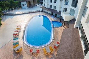 an overhead view of a large swimming pool with chairs and umbrellas at AJ GRAND ELITE HOTEL in Mangalore